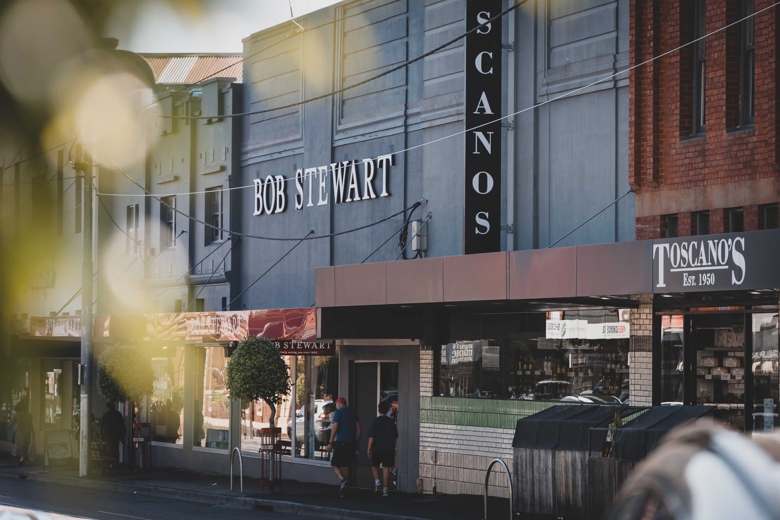 Independent shops and established trees at Kew Junction.
